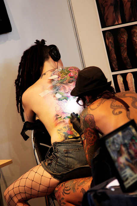 A tattooist working on a back piece